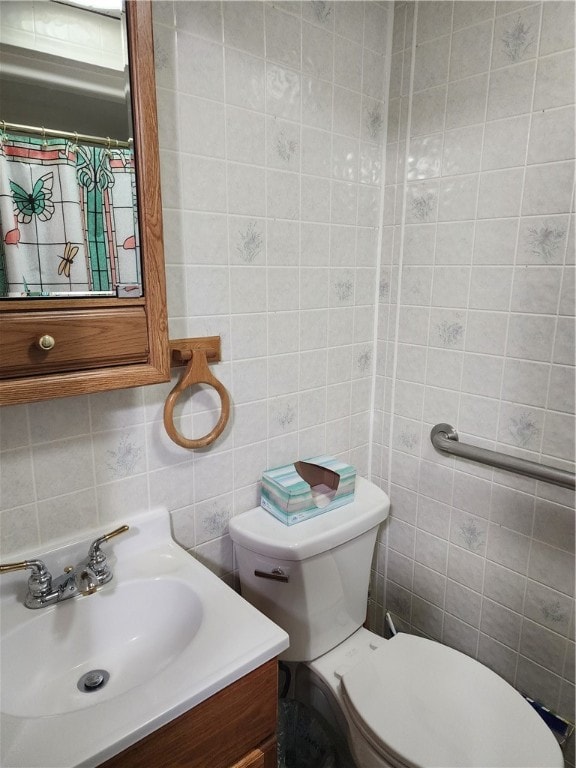 bathroom with toilet, walk in shower, tile walls, vanity, and tasteful backsplash