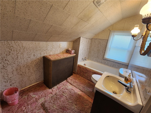 bathroom with vanity, vaulted ceiling, a relaxing tiled tub, and toilet