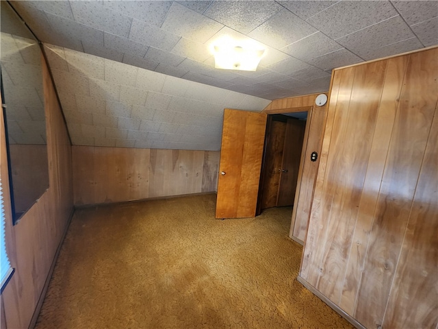 additional living space featuring lofted ceiling, light carpet, and wood walls