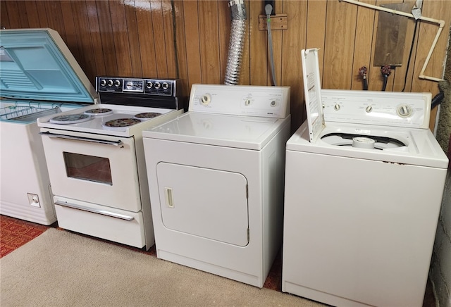 laundry area with light carpet, wood walls, and separate washer and dryer