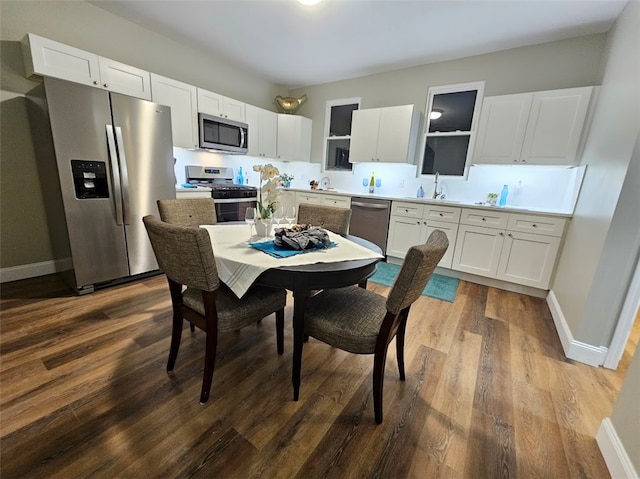 kitchen with appliances with stainless steel finishes, white cabinetry, hardwood / wood-style flooring, and sink