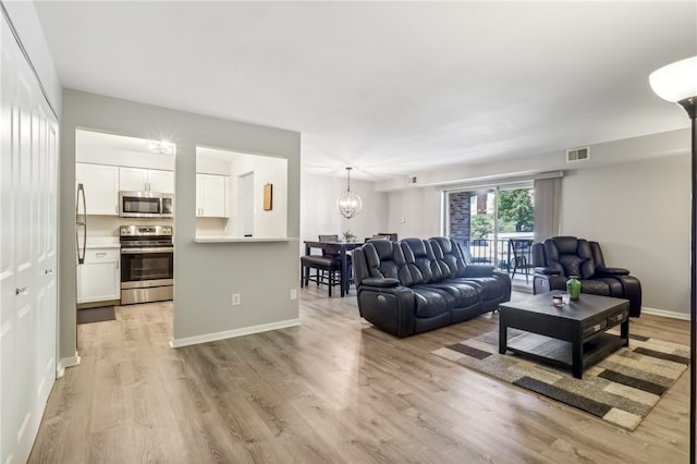 living room with an inviting chandelier and light hardwood / wood-style flooring