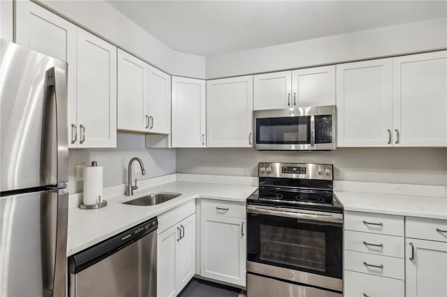 kitchen featuring light stone countertops, sink, appliances with stainless steel finishes, and white cabinets