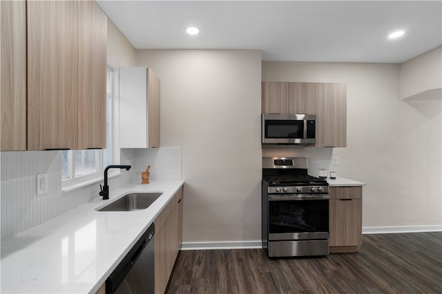 kitchen featuring dark wood-type flooring, stainless steel appliances, backsplash, sink, and light stone counters