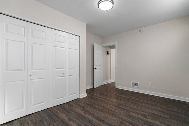 unfurnished bedroom with a closet and dark hardwood / wood-style floors