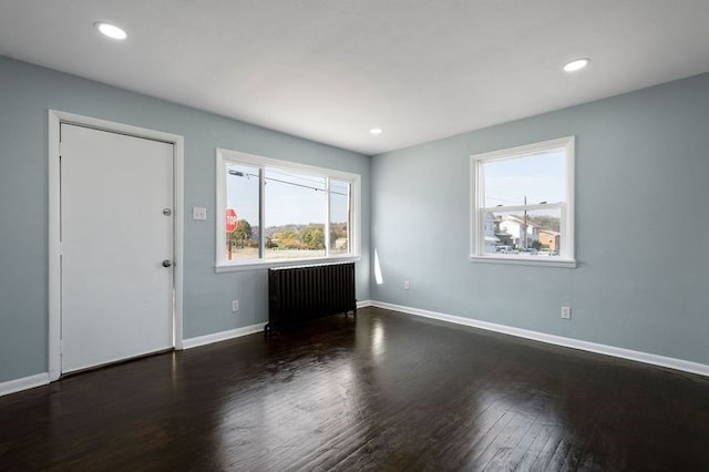 interior space featuring dark hardwood / wood-style floors, radiator heating unit, and a healthy amount of sunlight