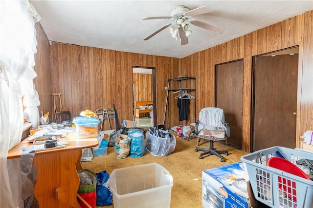 miscellaneous room with ceiling fan, carpet, and wood walls