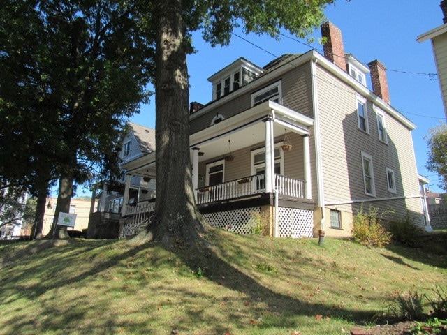 view of side of home featuring covered porch and a lawn