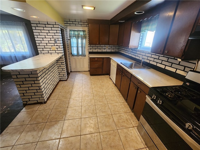 kitchen featuring gas range oven, sink, dark brown cabinets, and backsplash