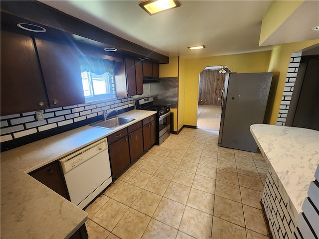 kitchen featuring tasteful backsplash, appliances with stainless steel finishes, sink, dark brown cabinets, and light tile patterned floors