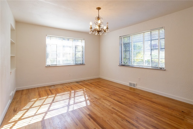 empty room featuring a notable chandelier and hardwood / wood-style floors