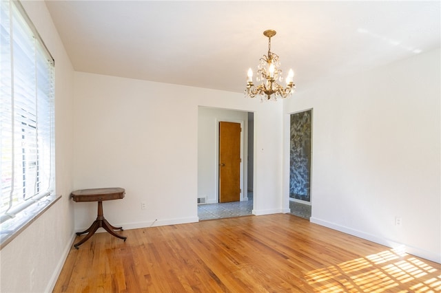 empty room featuring a chandelier and light wood-type flooring