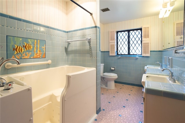 bathroom featuring a washtub, toilet, tile walls, vanity, and tile patterned flooring