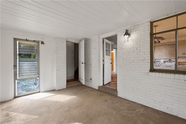 spare room featuring brick wall and wood ceiling