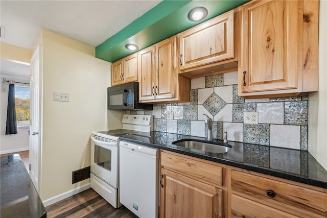 kitchen with dark wood-type flooring, backsplash, dark stone counters, sink, and white appliances