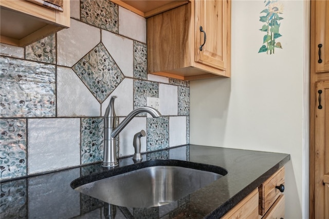 kitchen featuring dark stone countertops, sink, and backsplash