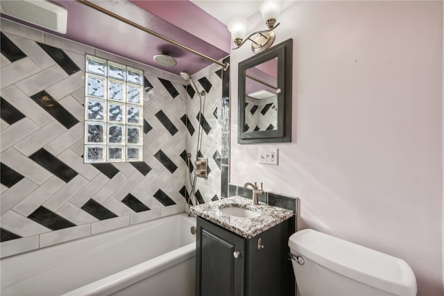 full bathroom featuring vanity, tiled shower / bath, and toilet