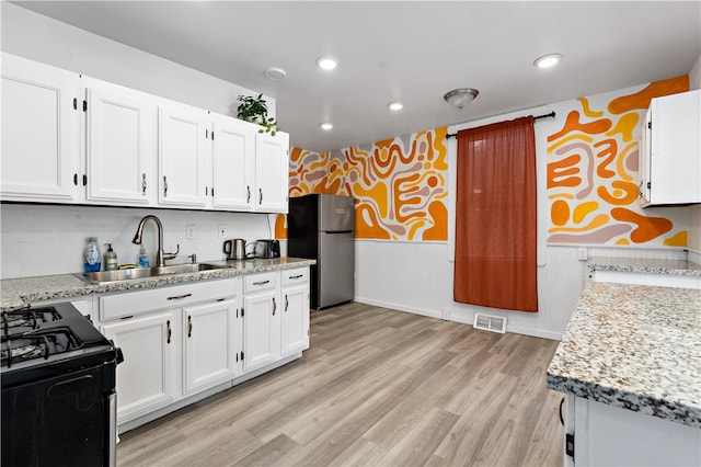 kitchen with white cabinetry, stainless steel refrigerator, light hardwood / wood-style flooring, and sink