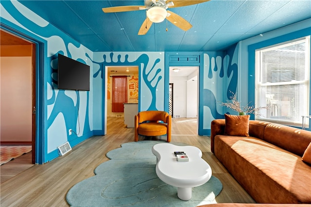 living room featuring a textured ceiling, wood-type flooring, and ceiling fan