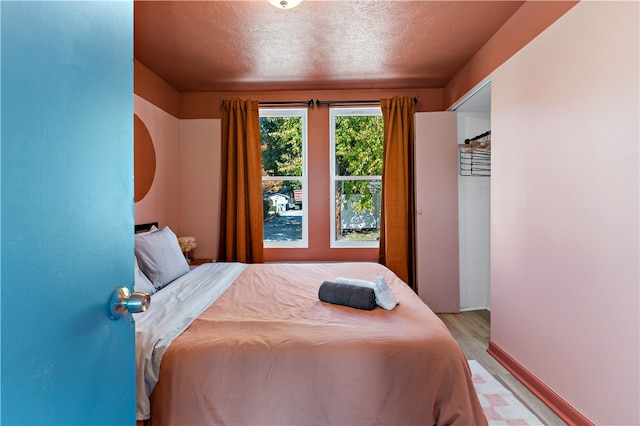 bedroom with a textured ceiling and light wood-type flooring