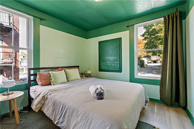 bedroom with multiple windows and hardwood / wood-style flooring