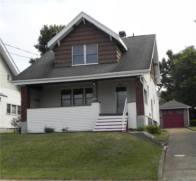 bungalow with covered porch, a garage, an outbuilding, and a front lawn