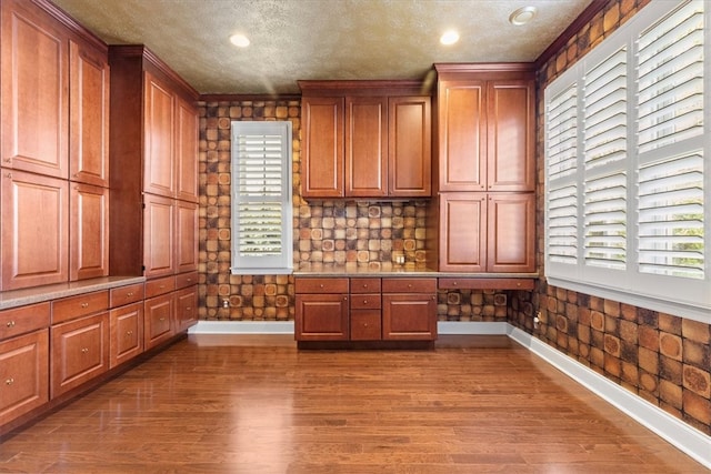 unfurnished office with crown molding, a textured ceiling, and dark hardwood / wood-style flooring