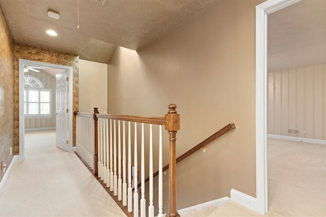 corridor featuring light carpet and a textured ceiling