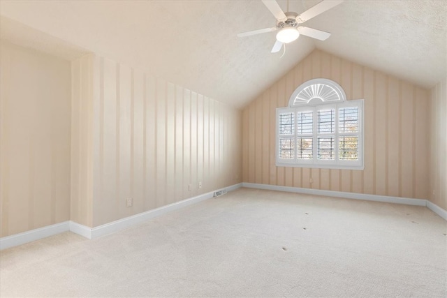 carpeted spare room with lofted ceiling, a textured ceiling, and ceiling fan