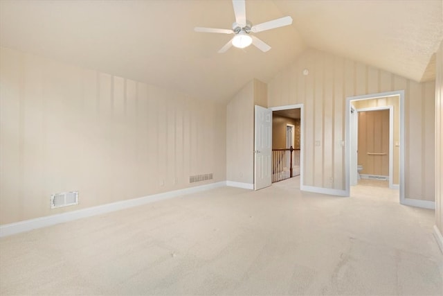 unfurnished bedroom featuring light colored carpet, ceiling fan, vaulted ceiling, and ensuite bathroom