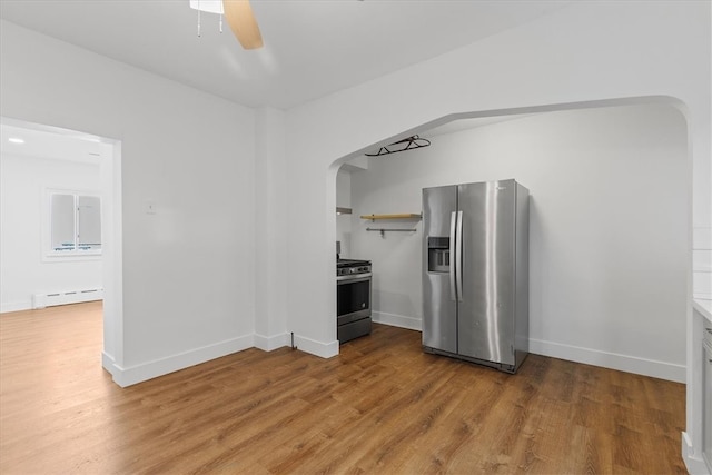 kitchen with a baseboard radiator, ceiling fan, stainless steel appliances, and hardwood / wood-style flooring