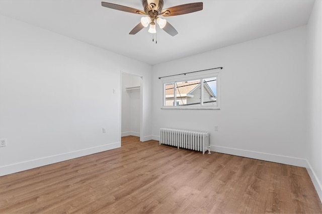 empty room featuring light hardwood / wood-style flooring, radiator heating unit, and ceiling fan