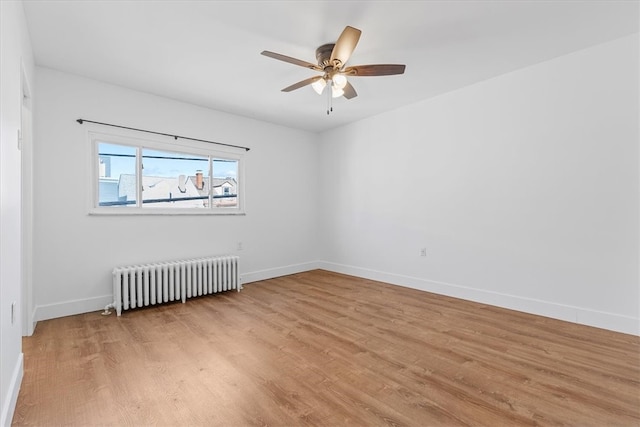 empty room featuring light hardwood / wood-style flooring, radiator, and ceiling fan