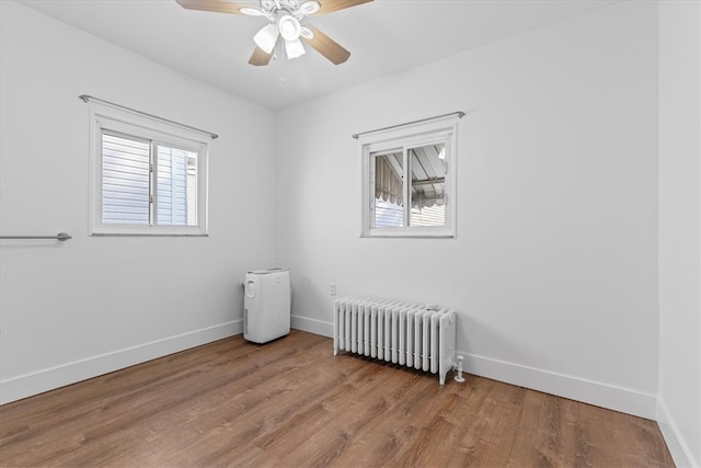 empty room with wood-type flooring, radiator, and plenty of natural light