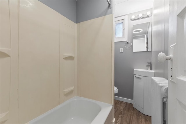 full bathroom featuring washtub / shower combination, radiator heating unit, hardwood / wood-style floors, toilet, and vanity