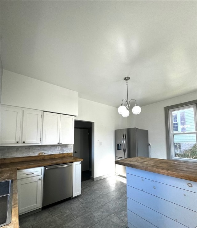 kitchen with appliances with stainless steel finishes, wood counters, white cabinetry, a notable chandelier, and decorative light fixtures