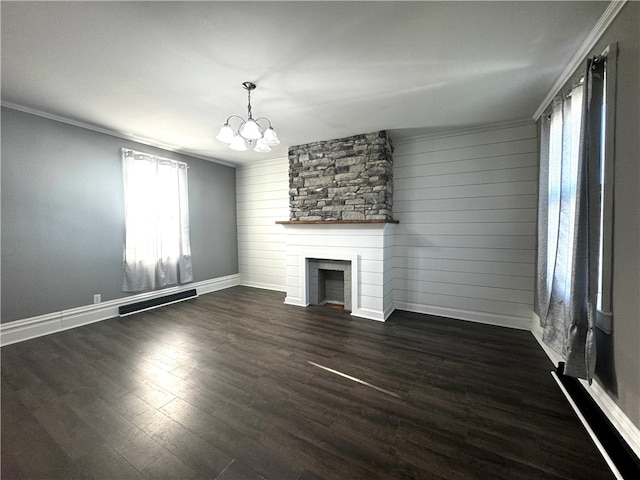 unfurnished living room with a stone fireplace, ornamental molding, dark hardwood / wood-style flooring, and a chandelier