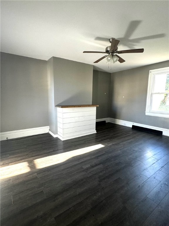 empty room with ceiling fan, dark hardwood / wood-style flooring, and a fireplace