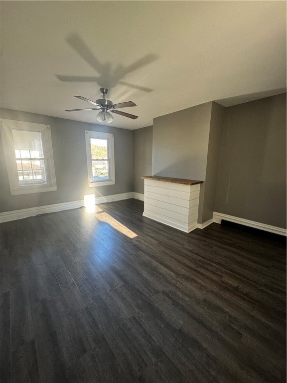 unfurnished room with ceiling fan, a fireplace, and dark hardwood / wood-style flooring