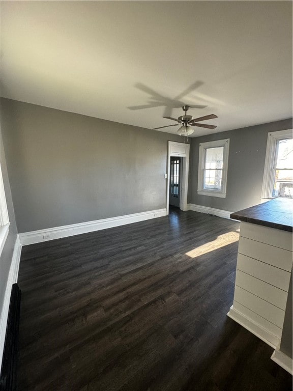 unfurnished living room with ceiling fan, a baseboard heating unit, and dark hardwood / wood-style floors