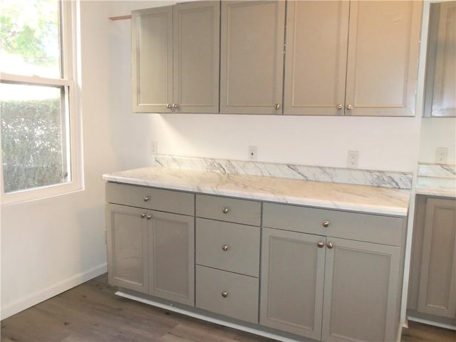 kitchen featuring gray cabinetry, dark hardwood / wood-style flooring, and light stone counters