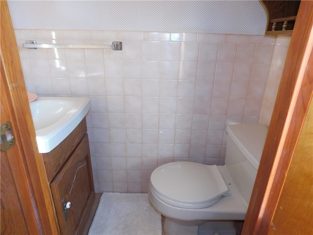 bathroom featuring tile walls, vanity, and toilet