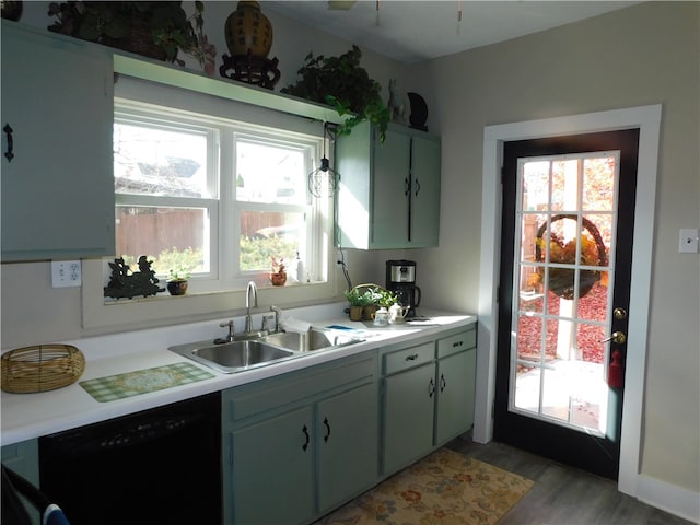 kitchen featuring light hardwood / wood-style flooring, green cabinets, black dishwasher, and sink