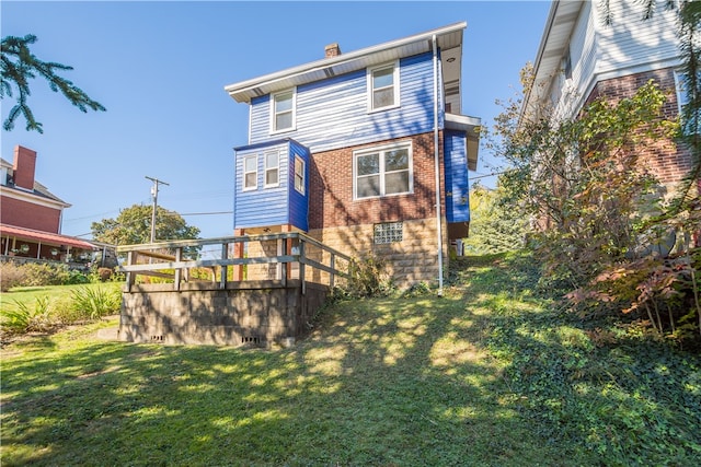 rear view of house with a wooden deck and a lawn