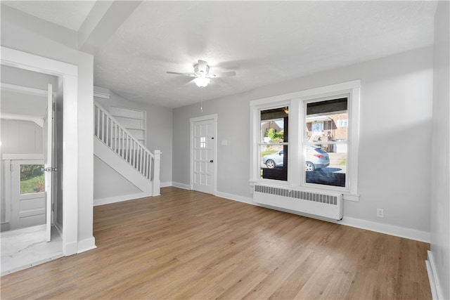 entryway with radiator heating unit, a textured ceiling, light wood-type flooring, and ceiling fan