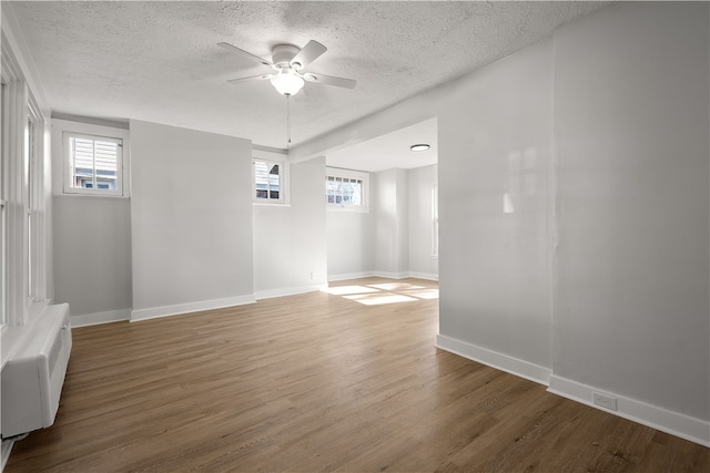 empty room with a textured ceiling, hardwood / wood-style flooring, and plenty of natural light