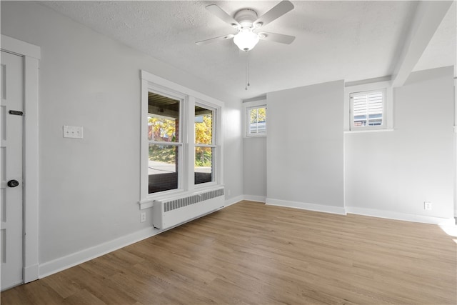 unfurnished room featuring radiator, light hardwood / wood-style floors, a textured ceiling, and ceiling fan