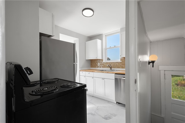 kitchen with white cabinets, tasteful backsplash, appliances with stainless steel finishes, wood counters, and sink