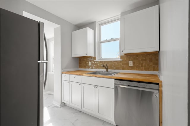 kitchen featuring wooden counters, sink, white cabinetry, appliances with stainless steel finishes, and tasteful backsplash