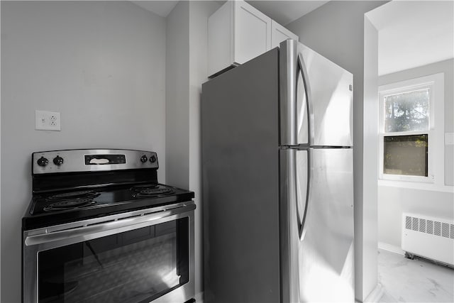 kitchen with appliances with stainless steel finishes, radiator heating unit, and white cabinetry